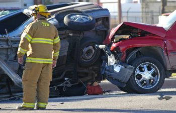 A firefighter next to two wrecked cars after a serious accident.