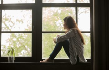 A depressed woman sitting by the window.