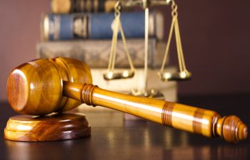 Defence Lawyer's desk with a judge's gavel, scales and legal books.